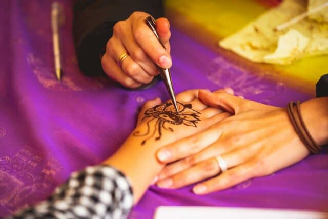 Close-Up Photo of Person Doing Mehndi Tattoo